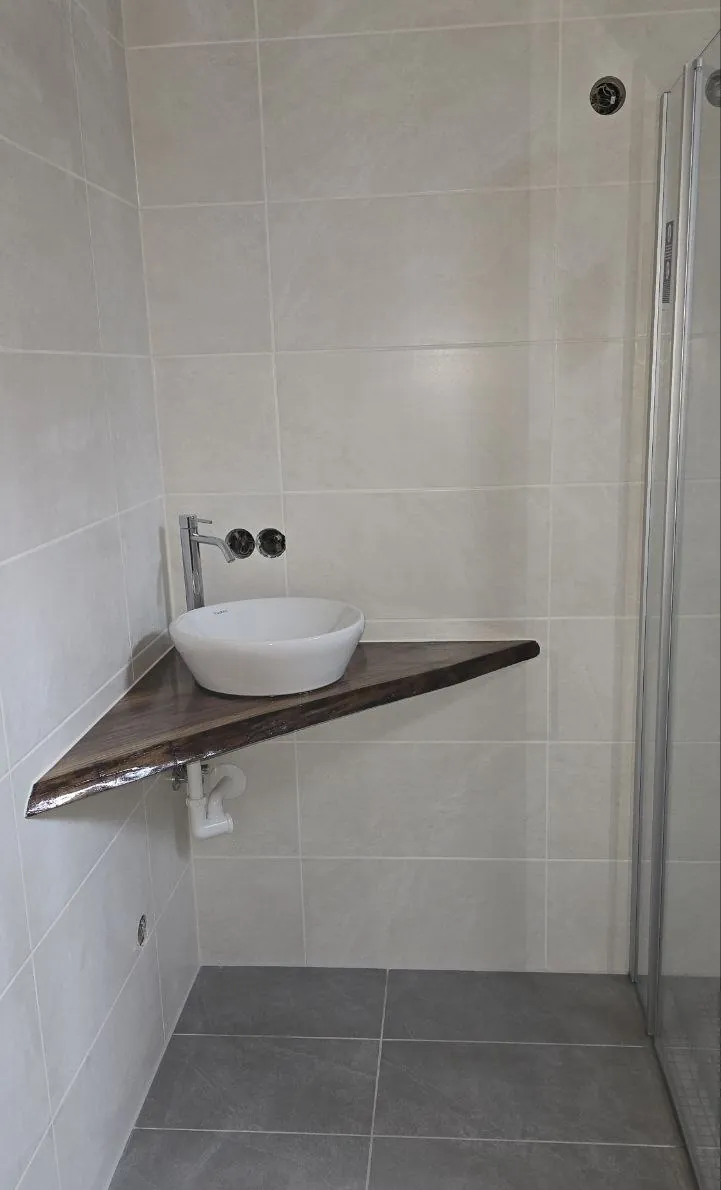 Aufsatzwaschbecken auf einer Holzplatte mit Baumkante in der Badecke