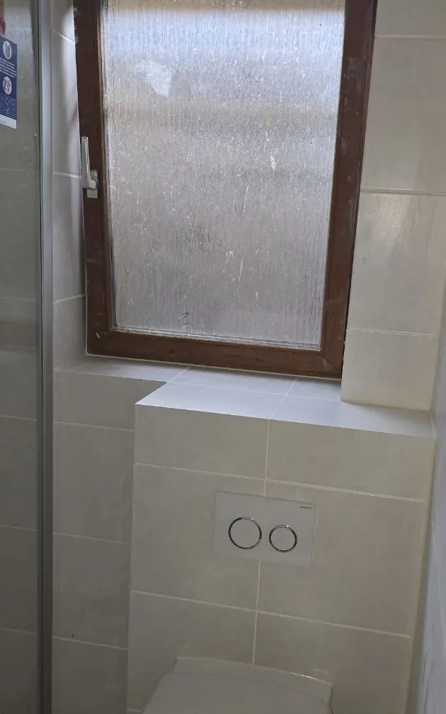 Nachher: dasselbe Bad, neu gefliest mit Wand-WC unter dem Fenster