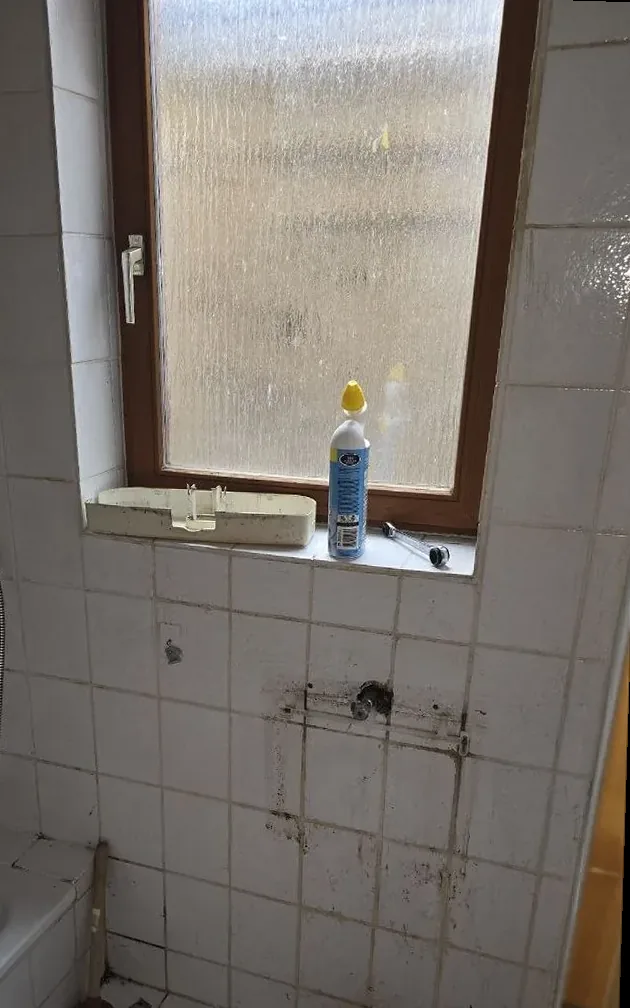 Vorher: altes Bad mit fleckigen Fliesen unter dem Fenster